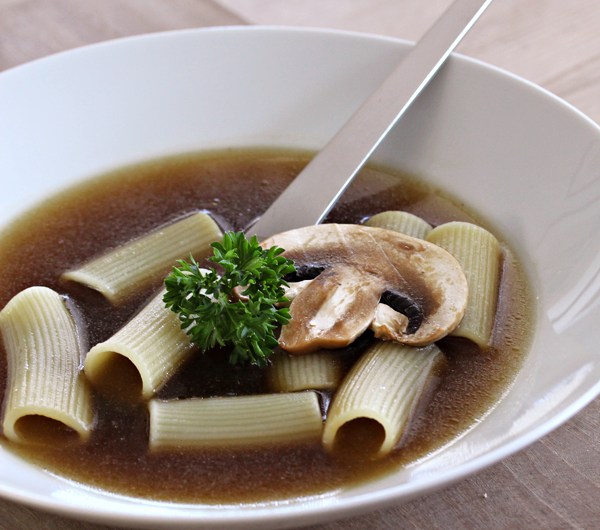 Tallerken med klar soppsuppe med pasta
